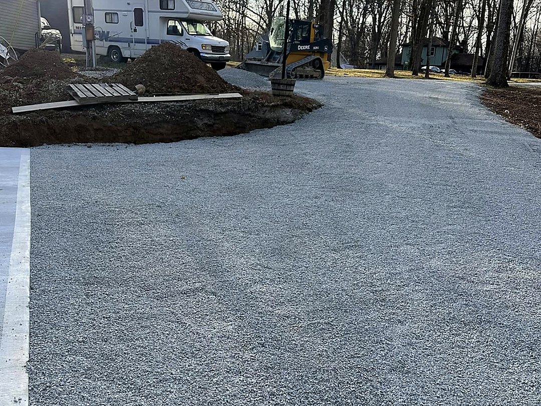 Freshly spread and rolled driveway stone running between mature trees