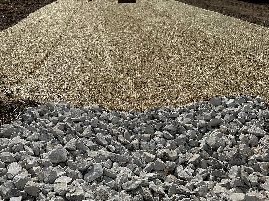 Pile of clean driveway stone staged on a graded pad ready to spread