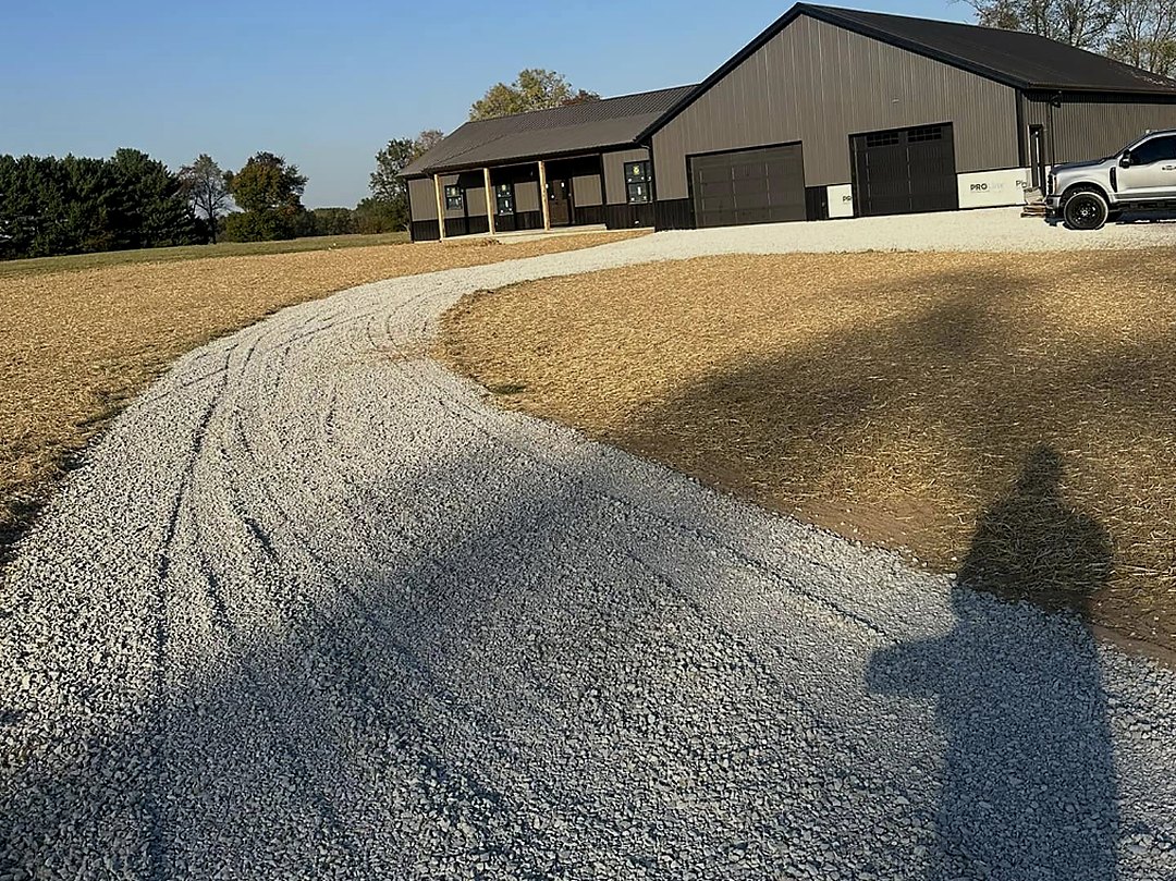 Long gravel driveway sweeping in a curve toward a single-storey home
