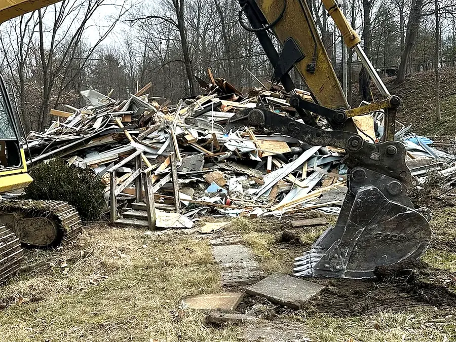 Excavator sorting demolition debris into a pile on a cleared site