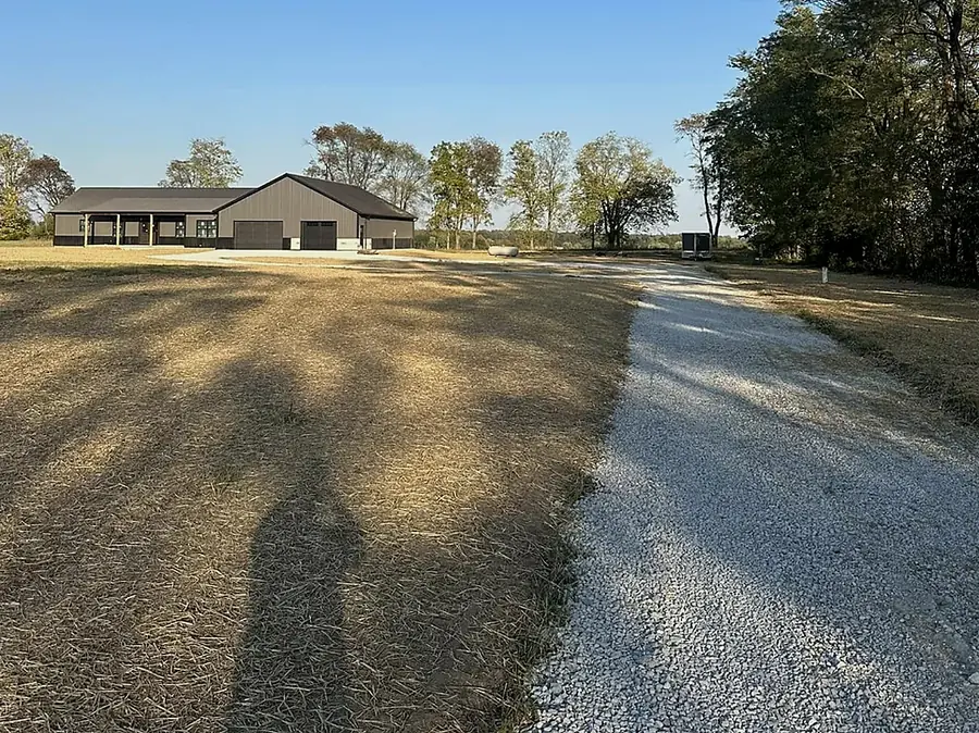 Gravel approach drive photographed down its length toward a house at dusk