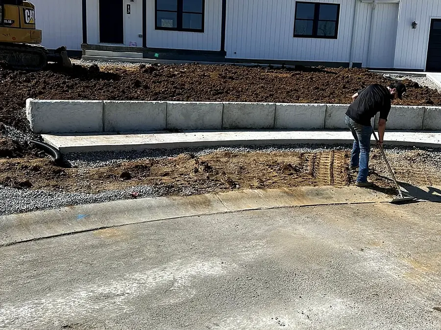 Poured foundation wall at a new house with backfill being worked along its face