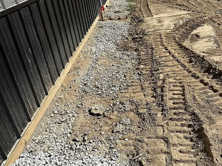 Graded stone strip along the base of a dark metal building wall