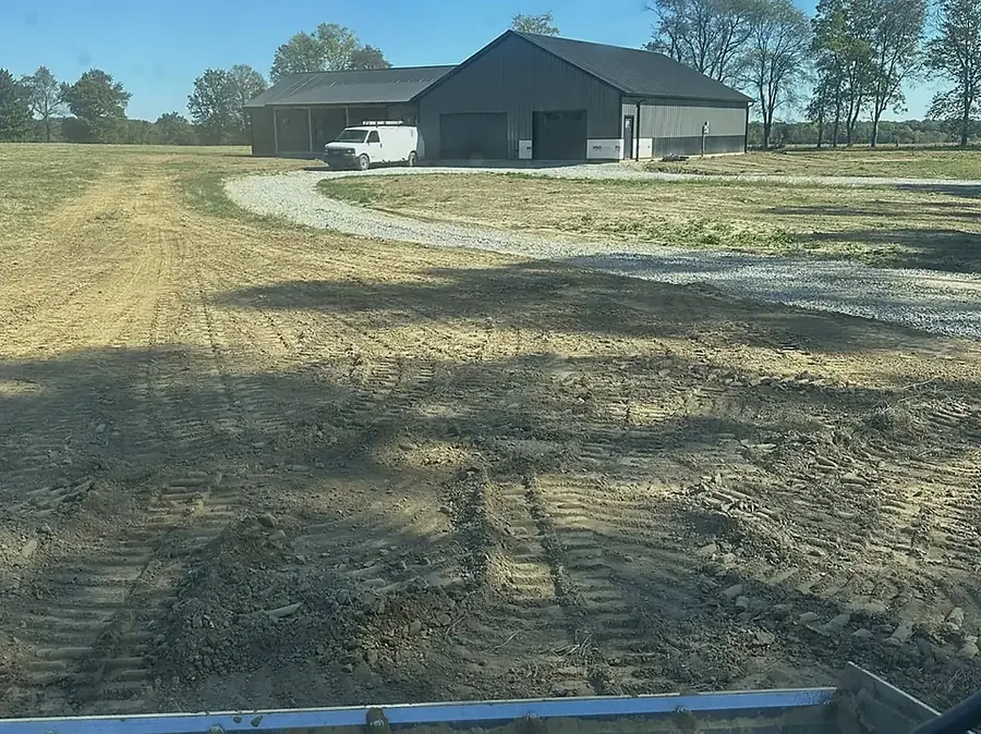 Pond dug at the edge of an open field with a building beyond