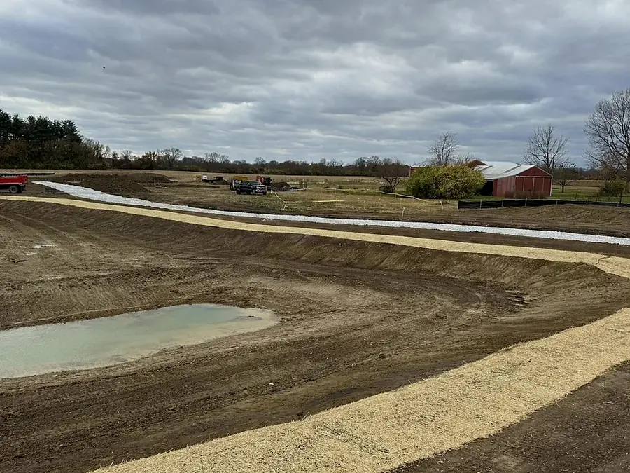 Excavated pond basin with water standing and the spoil graded out around it
