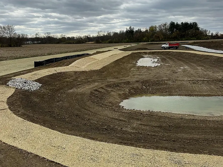 Newly excavated pond with shaped and graded banks holding first water