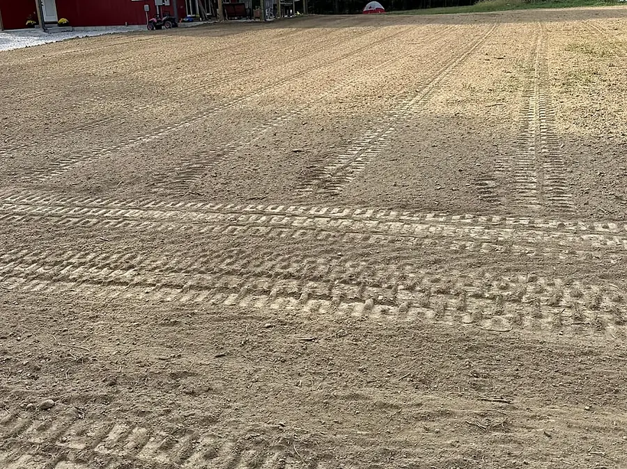 Smooth graded and raked yard in front of a red barn ready for seed
