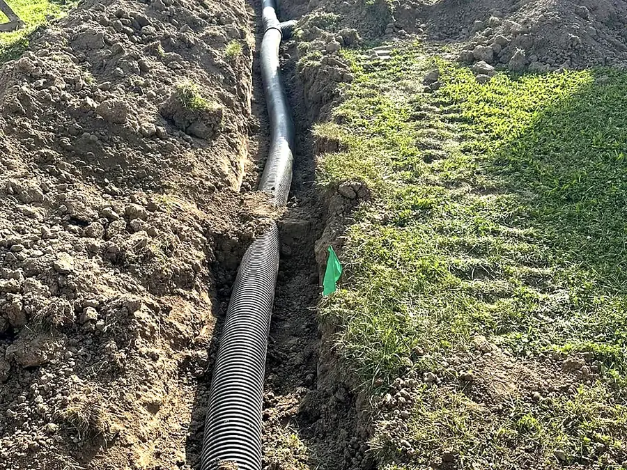 Drainage pipe run laid across a lawn before backfilling
