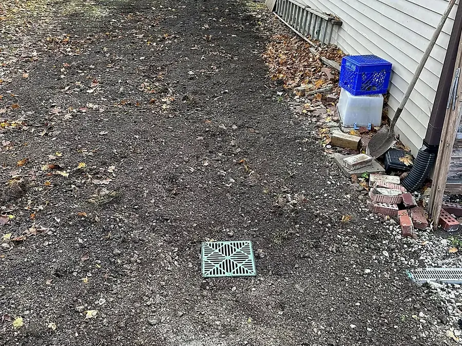 Backfilled and stone-topped trench line beside a residential foundation