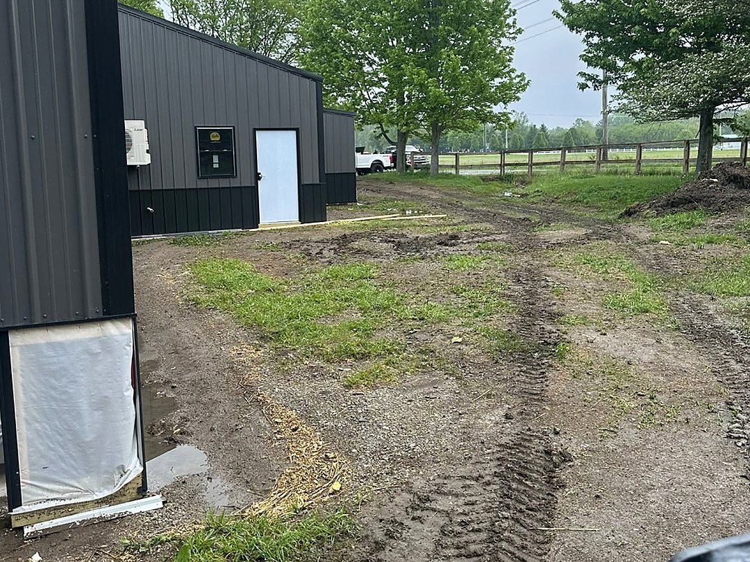 Stripped and levelled ground behind a metal building, staked and ready