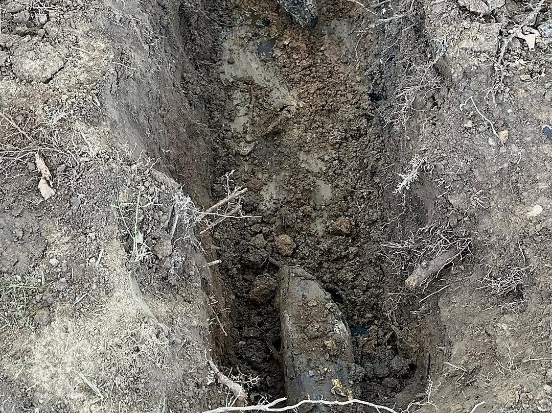 Open trench cut through heavy clay showing bucket teeth marks